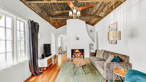 A spacious living room with a wooden ceiling, a fireplace, a television, and a sofa. - Spanish Beach Bungalow (Holly Hill)