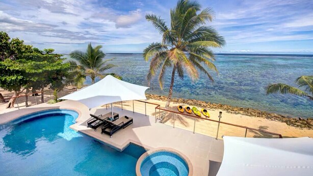 Un espace piscine avec des chaises longues, un petit jacuzzi rond et une vue sur l’océan.