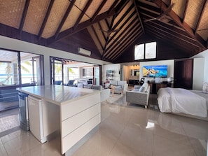 A spacious living area with a kitchen island, a dining area, and a bedroom with a large bed.