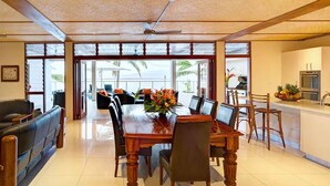 Un vaste espace dédié à la salle à manger, avec une table et des chaises en bois, un ventilateur de plafond et une vue sur l’extérieur.