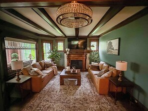 Ein traditionell eingerichtetes Wohnzimmer mit Kamin, zwei Sofas, einem Couchtisch und einer Chandelier.
