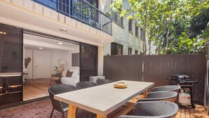 Eine Terrasse im Freien mit einem Esstisch, Stühlen und einem Grill.
