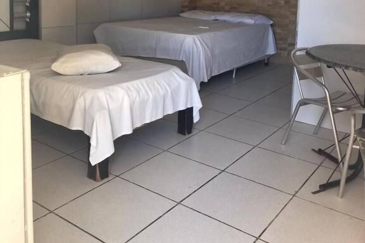Une petite chambre propre, avec deux lits simples, une petite table et une chaise.