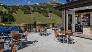 Eine Terrassenanlage im Freien mit Sitzgelegenheiten und einer Bar, mit Blick auf eine gebirgige Landschaft.