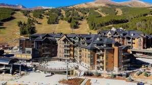 Ein mehrstöckiges Hotel mit einer Skipiste im Hintergrund.