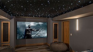 Ein Heimkino mit großer Leinwand, bequemen Sitzgelegenheiten und einer sternenklaren Decke.