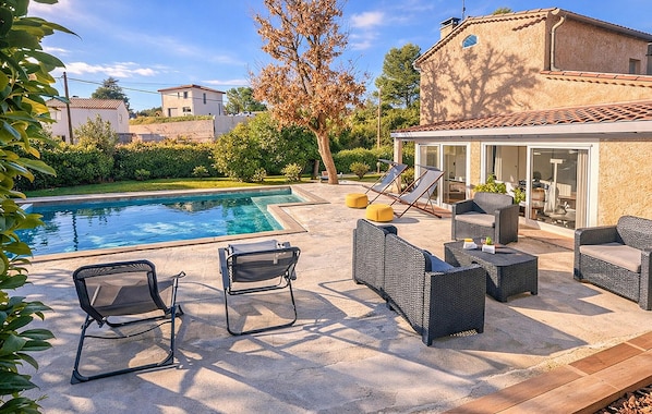 A pool area with lounge chairs and a covered seating area.