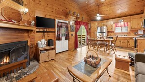 Ein Ferienhausinnenraum mit Kamin, Holzböden, Essbereich und Küche.