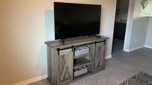 A living room with a flat-screen TV mounted on a wooden entertainment center with open shelving. - Minutes from Kingman Regional Medical Center (Kingman)
