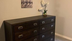 A dark wooden dresser with multiple drawers and silver handles, placed against a wall with a framed picture above it. - Minutes from Kingman Regional Medical Center (Kingman)