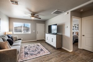 A living room with a sofa, TV, and decorative rug. - Route 66 Overnight with RV Gate + Fenced Yard (Kingman)