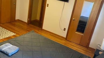 A bedroom with a bed, a ceiling fan, a TV mounted on the wall, and wooden doors.