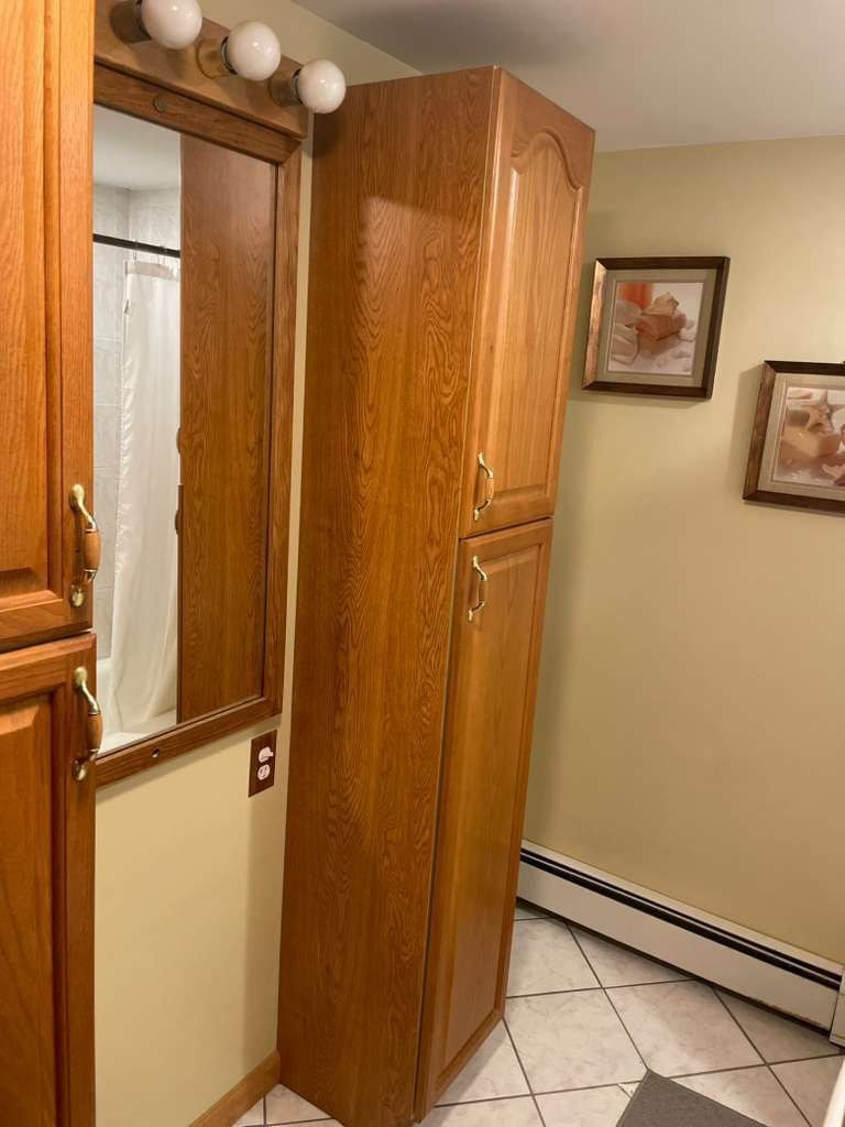 Un armario de madera con espejo y una lámpara sobre él.