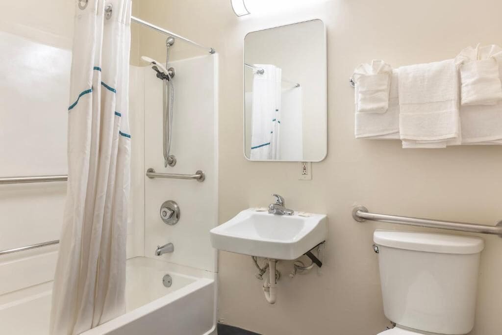 A bathroom with a shower, a sink, a toilet, and a mirror.