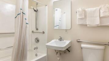 A bathroom with a shower, a sink, a toilet, and a mirror.