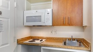 Una cucina compatta con forno a microonde, fornello e lavandino.