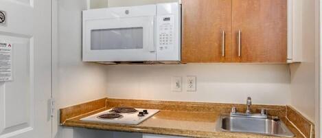 A compact kitchen with a microwave, stove, and sink.