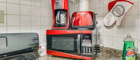 A kitchen with a red microwave, a coffee maker, and a bottle of Ajax Ultra dish soap.
