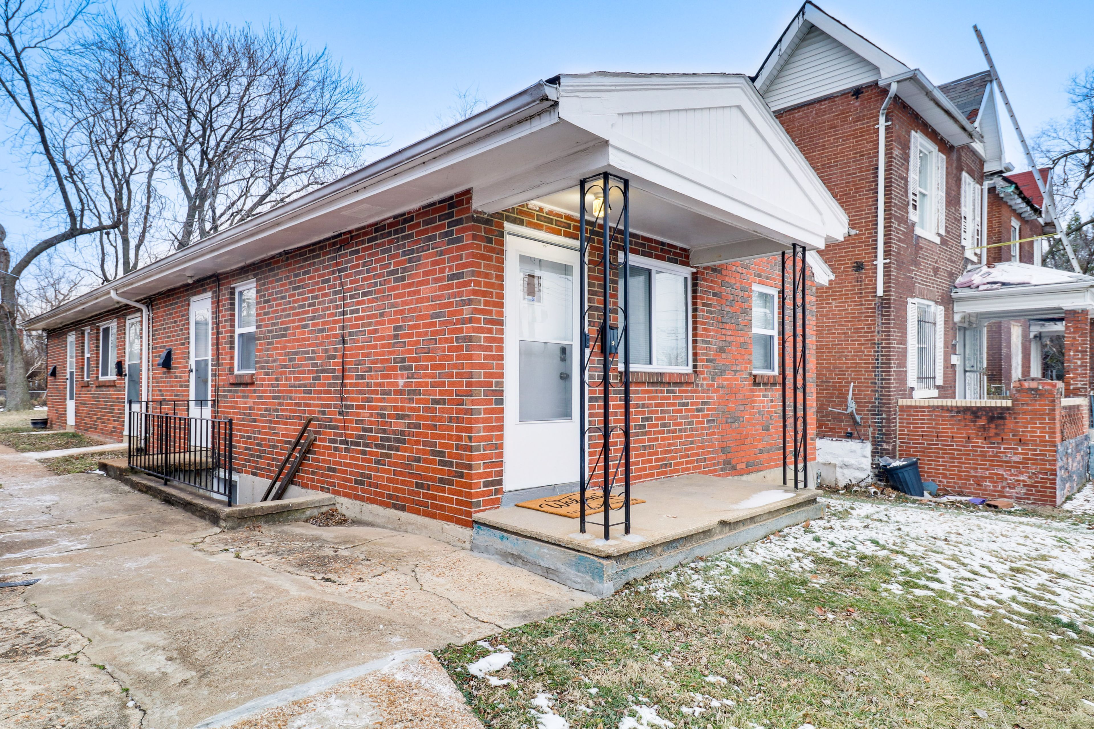 A two-story brick house with a front porch, a garage, and a small front yard.