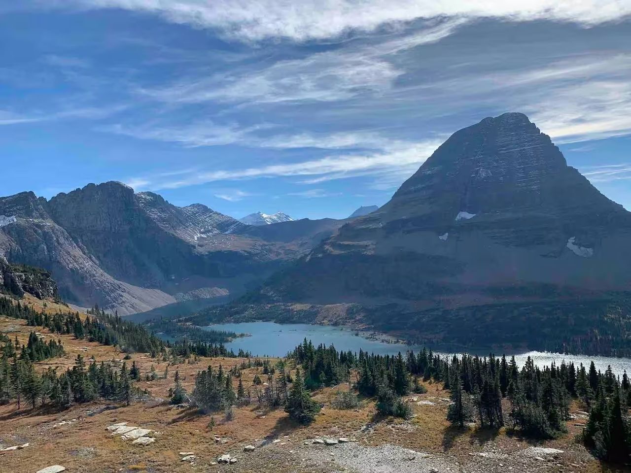 A panoramic outdoor view of towering mountains and a lake in the valley below.