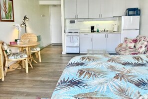 A room with a bed, a dining table with chairs, a kitchenette, and a sofa. - Stylish Studio- Stunning City View - Parking (Honolulu)