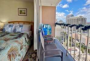 A balcony with a bed, a chair, and a view of the cityscape. - Stylish Studio- Stunning City View - Parking (Honolulu)