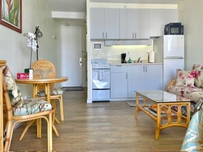 A compact living space with a kitchenette, a dining area with a round table and chairs, and a sofa with floral upholstery. - Stylish Studio- Stunning City View - Parking (Honolulu)