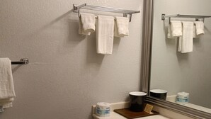 A bathroom with a toilet, a sink, a mirror, and a towel rack.