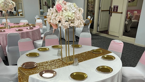 A conference room with round tables, white chairs with pink sashes, and floral centerpieces. - Economy Inn of Reading (Reading)