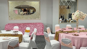 A conference room with white chairs, a pink tablecloth, and a large mirror on the wall. - Economy Inn of Reading (Reading)