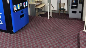 A lobby with a Pepsi vending machine, a map, a small table with a vase of flowers, and a seating area with a chair and a stool. - Economy Inn of Reading (Reading)