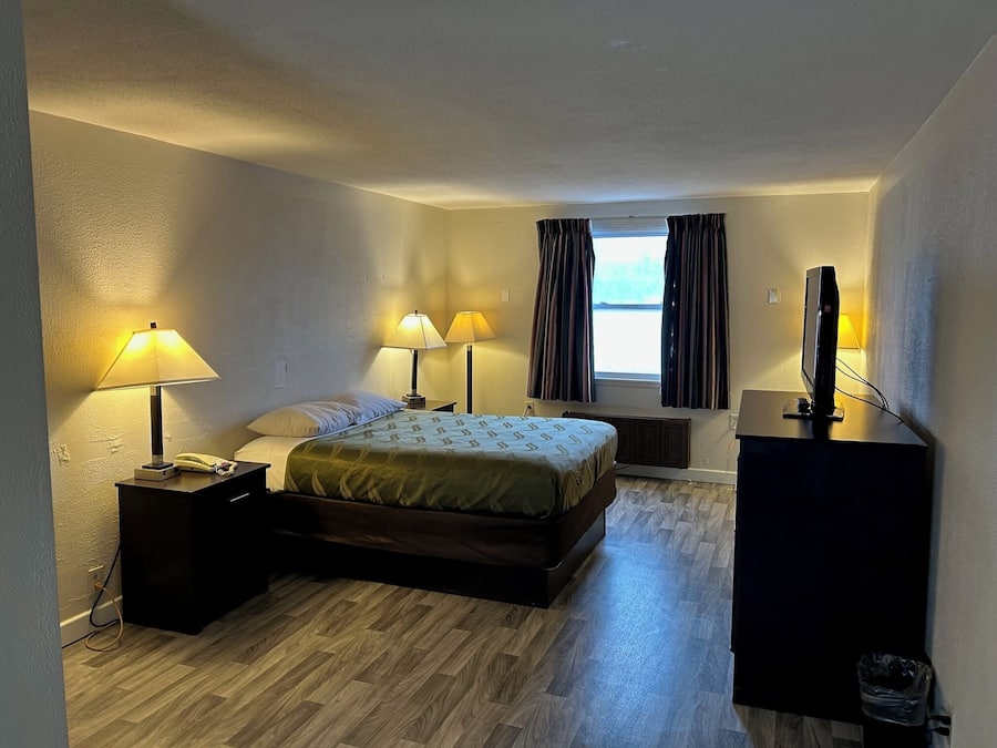 A hotel room with a bed, bedside lamps, a desk with a computer, and a window with curtains.