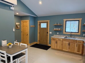 Een moderne keuken met houten kastjes, een granieten aanrechtblad en een raam met uitzicht op bomen.