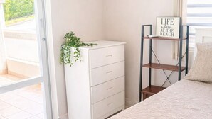 A bedroom with a bed, a dresser, a potted plant, a sign, and an air conditioning unit. - Tranquil Campo Home w/ Lush Private Outdoor Oasis (Daguao)
