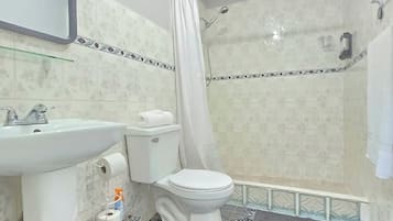 A bathroom with a toilet, sink, shower, and patterned floor tiles.