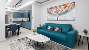 Een moderne woonkamer met een smaragdgroene bank, een marmeren bijzettafeltje en een kleurrijk abstract schilderij aan de muur.