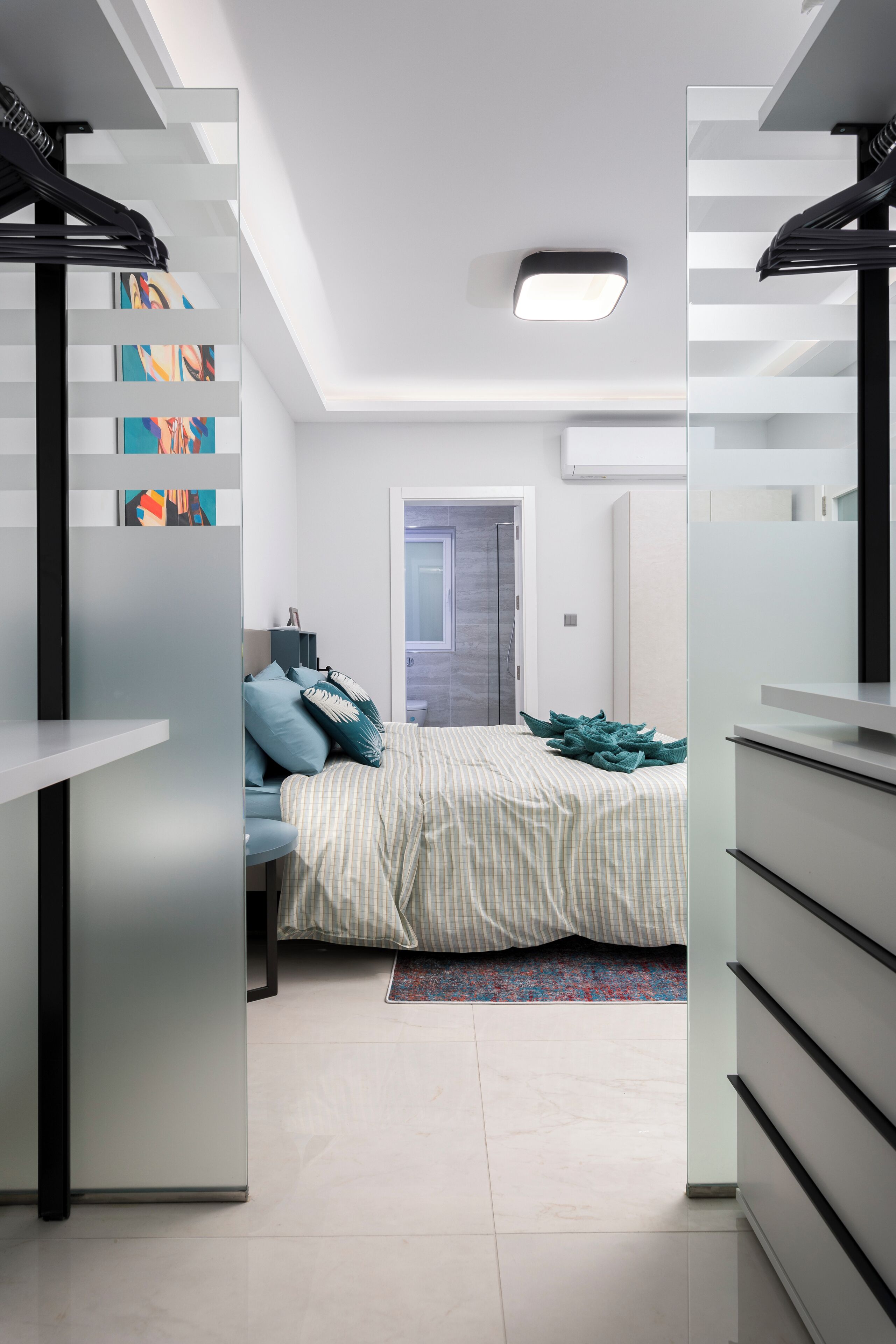 Un dormitorio moderno con cama, mesitas de noche, armario y un tragaluz.