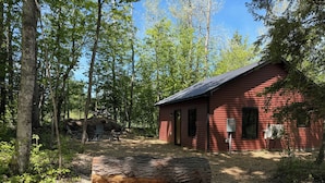 A red cabin with a gravel path leading to it, surrounded by trees. - Secluded cabin on the trails- cabin #1 (Petoskey)