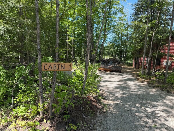 A cabin labeled 'CABIN 1' with a gravel path leading to it, surrounded by trees.