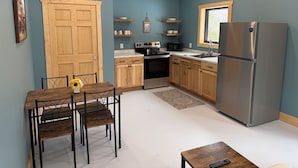 A compact kitchen with wooden cabinets, a stainless steel refrigerator, a microwave, and a stove. - Secluded cabin on the trails- cabin #1 (Petoskey)