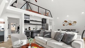 En moderne stue med sofa, sofabord og udsigt til køkkenet.