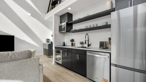 Et moderne køkken med rustfrie stålgadgetter, sorte skabe og en hems med udsigt.