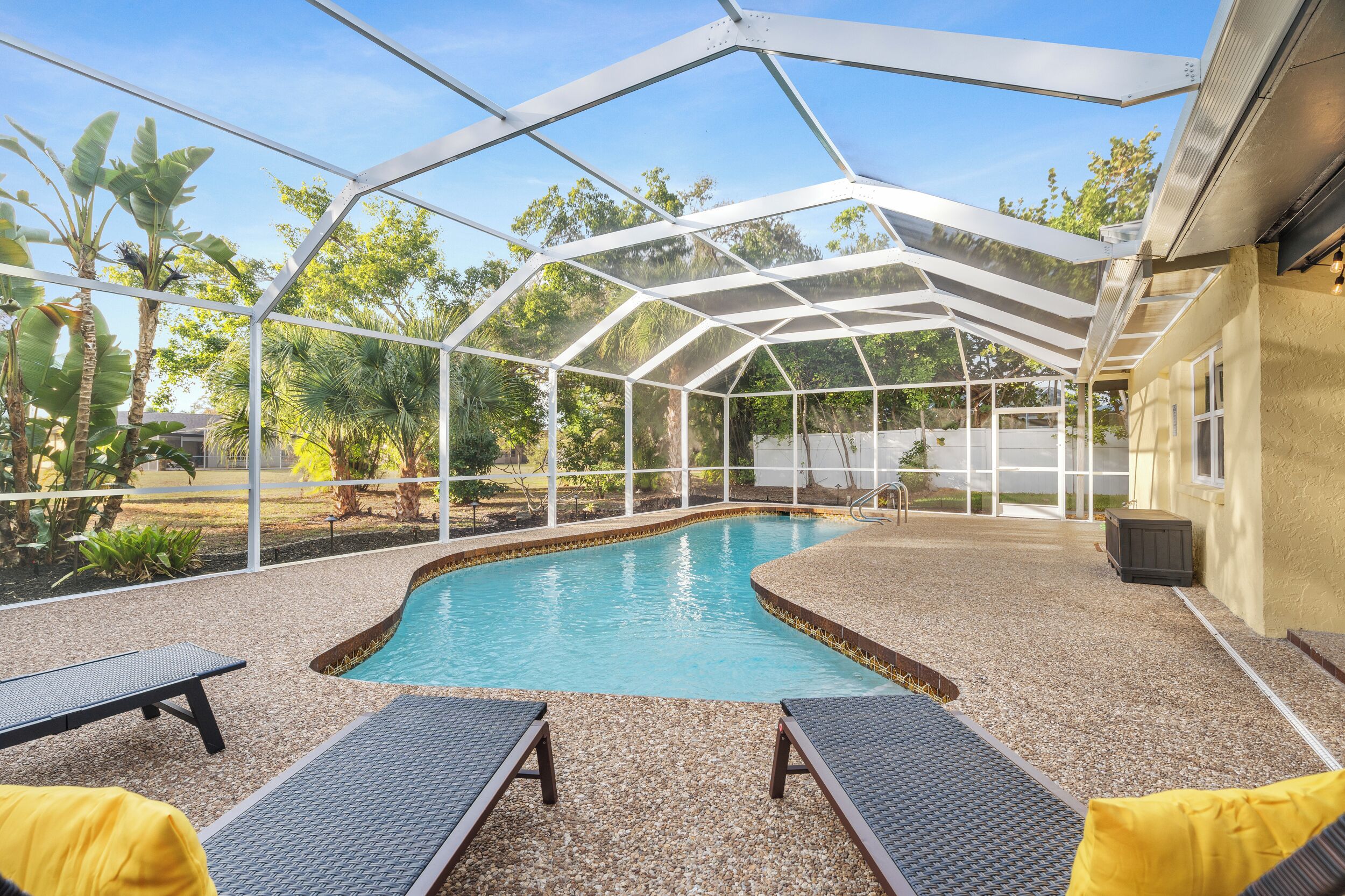 A covered outdoor swimming pool with lounge chairs and a pergola structure.