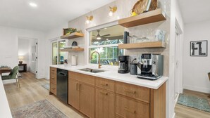 Een moderne keuken met houten kastjes, een wit aanrechtblad en ingebouwde planken.
