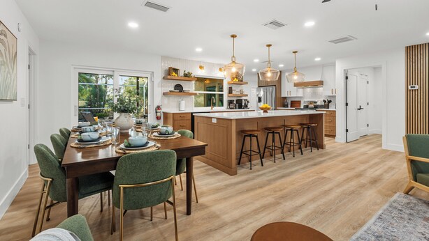 Een moderne keuken met een centraal eiland, barstoelen en hanglampen.