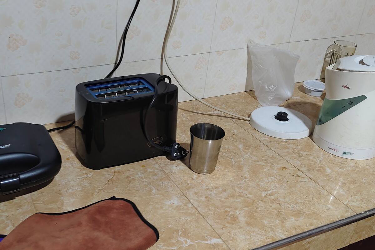 Un plan de travail de cuisine avec un grille-pain, une bouilloire, une machine à café et une tasse en acier inoxydable.