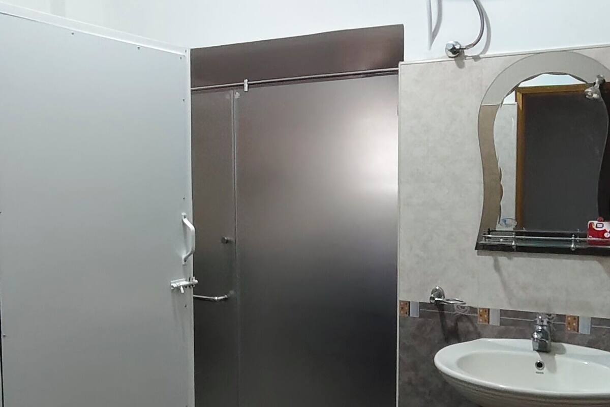 Une salle de bain avec un lavabo blanc, un miroir, un porte-serviettes et des toilettes.