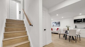 Eine moderne Wohnung mit einer Holztreppe, einem Essbereich mit Tisch und Stühlen sowie einer Küche mit Mikrowelle.