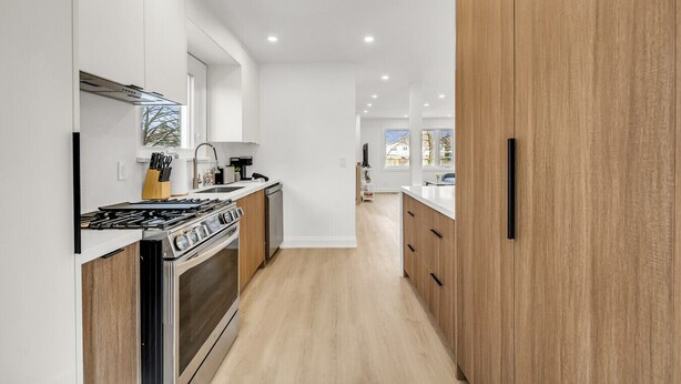 Una cocina moderna con armarios blancos, estufa de acero inoxidable y encimera de madera.