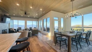 A spacious living area with a wooden ceiling, large windows offering mountain views, a dining table with chairs, and a fireplace. - Luxury Cabin w/ 180 Views, Hot Tub & Firepit Near Dollywood & Nat'l Park Bird's-eye View by Avantstay (Sevierville)